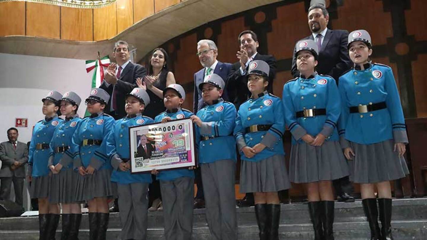 El homenajeado y demás funcionarios posaron con los niños gritones de la Lotería Nacional al concluir el sorteo de este 24 de octubre.