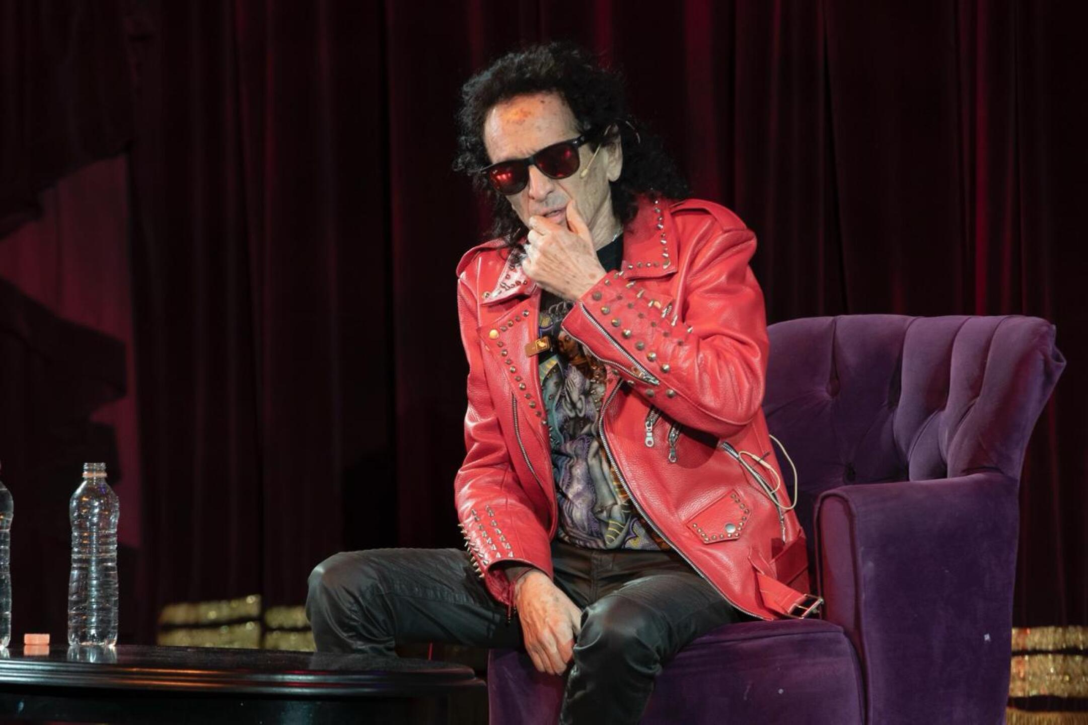 Alex Lora en el escenario del teatro sentado