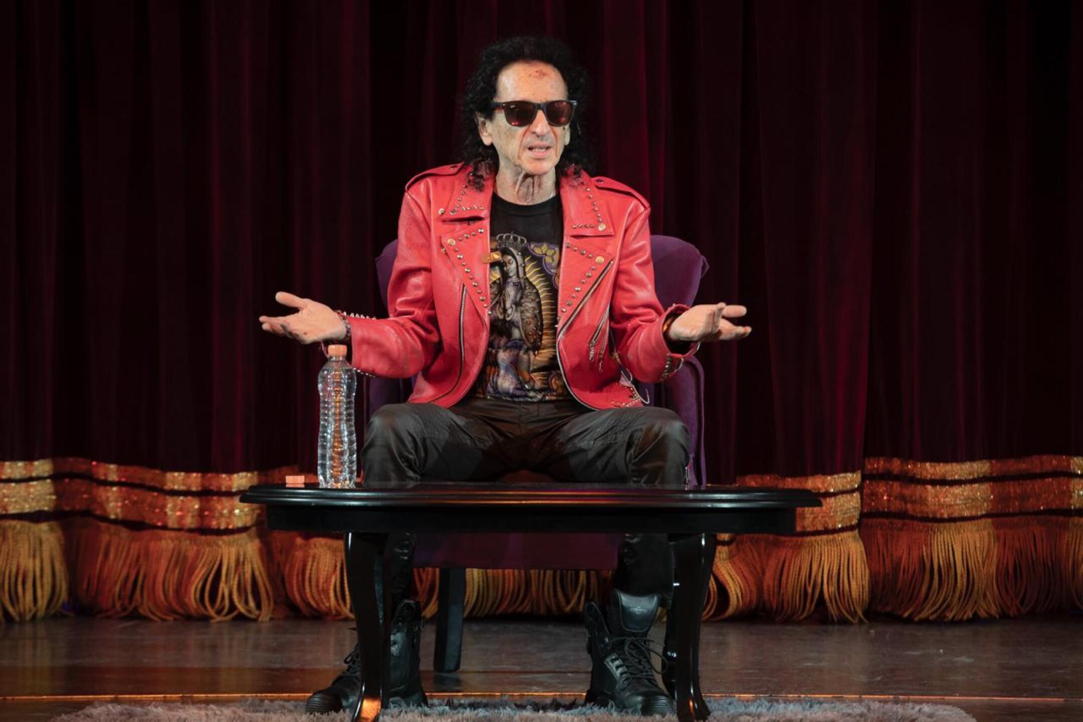 Alex Lora sentado en el escenario del teatro